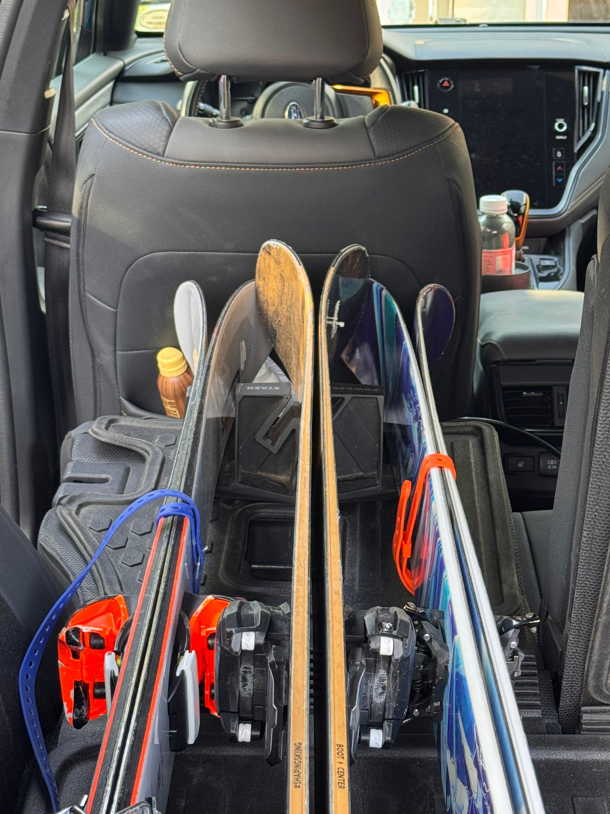 Skis stored upright inside a car with the Powder Stash holder