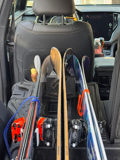Skis stored upright inside a car with the Powder Stash holder